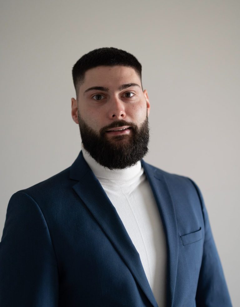 Inhaber Marc Derlich Derlo CP Ansprechpartner Ein Mann mit Bart, in Anzug und Krawatte, schaut direkt in die Kamera, als Sicherheitsberater.